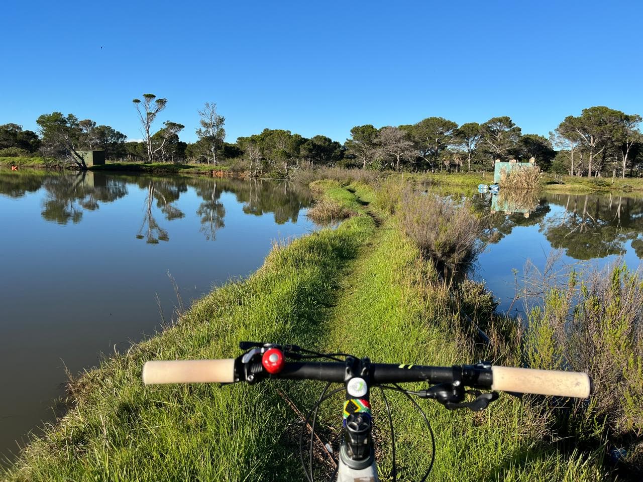 A mountain bike beside a winding PEGC trail and water